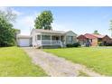 View of home with a driveway leading to a detached garage and a lush green lawn at 1020 N Ritter Ave, Indianapolis, IN 46219