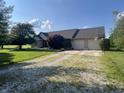 Home with two-car garage, gravel driveway, and basketball hoop near the garage at 1082 E County Road 400 S, Clayton, IN 46118