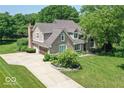 Beautiful home with a stone and siding exterior, complemented by a mature tree and a well-manicured lawn at 11030 Brentwood Ave, Zionsville, IN 46077