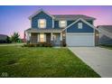 Charming two-story home at dusk featuring a well-manicured lawn and a two-car garage at 1278 W Limestone Way, Fortville, IN 46040