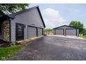 Detached two car garage with a black door, and additional shed space surrounded by asphalt driveway at 16714 Oak Rd, Westfield, IN 46074