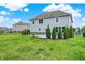 Exterior view of the home showcasing the backyard with a well-manicured lawn and neatly trimmed evergreen trees at 2074 Tompkins Dr, Westfield, IN 46074