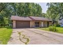 Single-story brick home showing driveway and attached garage, surrounded by mature trees at 436 N 500 W, Anderson, IN 46011