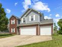 Charming two-story home featuring a two-car garage, brick accents, and gray siding at 6563 Enclave Blvd, Greenwood, IN 46143