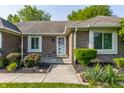 Inviting front entrance with a patterned welcome mat, lush greenery, and brick facade at 8117 Scarborough Ct, Indianapolis, IN 46256