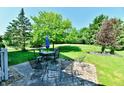 A stone patio features multiple seating areas, all surrounded by a lush, manicured lawn and beautiful landscaping at 8460 Brittany N Ct, Indianapolis, IN 46236