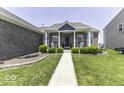 Inviting front porch featuring classic rocking chairs, brick facade, and manicured landscaping for a cozy welcome at 8864 S Tibbs Ave, Indianapolis, IN 46217