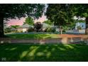 Charming single-story brick home with a beautiful lawn, mature trees, and a circular driveway at sunset at 9420 N Kenwood Ave, Indianapolis, IN 46260