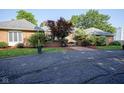 Charming brick home featuring manicured landscaping, beautiful bushes, and a paved driveway at 9420 N Kenwood Ave, Indianapolis, IN 46260