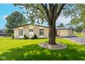 Brick home featuring a lush front yard with a large shade tree and decorative stone landscaping at 10622 Penn Dr, Indianapolis, IN 46280