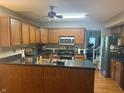 This kitchen boasts wood cabinets, black countertops, stainless steel appliances, and a dining area in the background at 11632 Coastal Way, Indianapolis, IN 46229