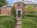 An ornate doorway on a brick home is flanked by manicured bushes and flowers at 1207 Pickwick Pl, Indianapolis, IN 46208