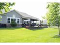 Lush backyard with a covered patio featuring outdoor seating and well-manicured lawn at 13820 Woodside Hollow Dr, Carmel, IN 46032