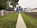Spacious backyard with a well-maintained lawn enclosed by a wooden fence, accessible by a long sidewalk at 1720 Rembrandt St, Indianapolis, IN 46202