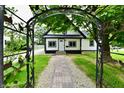 Charming home featuring a paved walkway leading to the front door viewed through an ornate metal garden arch at 2801 E Southport Rd, Indianapolis, IN 46227