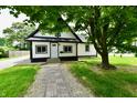 Charming home featuring a paved walkway leading to the front door and is shaded by mature trees at 2801 E Southport Rd, Indianapolis, IN 46227