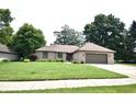 Well-manicured front yard showcasing the home's brick facade, complemented by lush greenery and mature trees at 5943 Red Maple Dr, Indianapolis, IN 46237