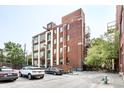 Brick apartment building with large windows, balconies, and a parking area with several cars at 624 E Walnut St # 48, Indianapolis, IN 46204
