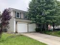 Two-story home featuring a two-car garage, siding, and a long driveway, complemented by lush landscaping at 7667 Madden Ln, Fishers, IN 46038