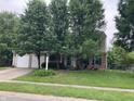 Charming two-story home featuring a well-maintained front yard with mature trees, lawn, and a driveway at 7667 Madden Ln, Fishers, IN 46038