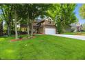 Beautiful two-story home featuring an attached garage, lush green lawn, and mature trees in a well-maintained yard at 8313 Tequista Cir, Indianapolis, IN 46236