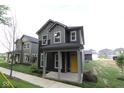Attractive two-story house featuring a covered porch, gray siding, a yellow door, and fresh landscaping at 9516 Bauhaus Way, Indianapolis, IN 46240