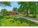 Ranch-style home with a long driveway and a well-manicured lawn, situated on a tree-filled lot at 108 Bennett Rd, Carmel, IN 46032
