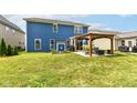 The home's blue exterior in the backyard has a large grass area and a stylish covered patio with outdoor furniture at 1314 Old Heritage Pl, Greenwood, IN 46143