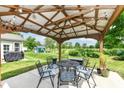Backyard covered patio featuring an outdoor dining set, a decorative overhead structure, and a serene backyard view at 1314 Old Heritage Pl, Greenwood, IN 46143