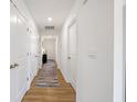 Clean, white hallway with multiple doors and a stylish rug on wood flooring at 24416 Kercheval St, Sheridan, IN 46069
