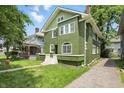 View of green two-story home with white trim, side yard, and driveway at 3307 N College Ave, Indianapolis, IN 46205