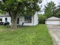 Side view of a white house featuring a lawn, tree, and detached garage at 3440 Brewer Dr, Indianapolis, IN 46222