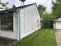 Exterior shot of home's side with white siding, gutter, and detached garage at 3440 Brewer Dr, Indianapolis, IN 46222