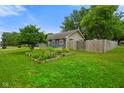 View of the side yard with established garden beds and wood fence at 50 Crestview Dr, Greenwood, IN 46143