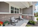 Inviting covered porch with brick accents, comfortable seating, and charming decorative details at 624 Faudree Dr, Westfield, IN 46074