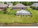 Aerial view of a backyard featuring an in-ground pool, deck, and fenced yard bordering a pond at 6629 Woodcrest Dr, Avon, IN 46123