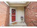 Charming entryway with brick walls, decorative wreath on the red door, and a lovely flower arrangement at 6637 Sundown S Dr, Indianapolis, IN 46254