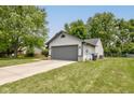 Side view of a two-car garage with gray door, siding, and driveway, surrounded by lawn and trees at 7239 Wet Rock Ct, Indianapolis, IN 46236