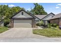 Charming home featuring a two-car garage, beautiful brick accents, and a well-maintained lawn at 7616 Derrek Pl, Indianapolis, IN 46219