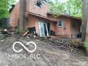 Exterior featuring a sliding door, damaged siding, and surrounding debris at 8803 S Sleepy Hollow Rd, Waldron, IN 46182