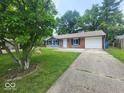 Inviting one-story home featuring a well-maintained lawn and a paved driveway leading to the garage at 9526 Burrwood Ct, Indianapolis, IN 46235
