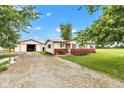 Inviting home exterior featuring a detached garage, gravel driveway, and lush front lawn at 10965 W Base Line Rd, Jamestown, IN 46147