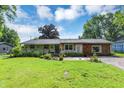 Charming single-story home with a lush green lawn, decorative foliage, and a combination brick and wood facade at 12606 Markay Dr, Fishers, IN 46038