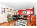 Cozy living room features a black leather sectional, vibrant red accent wall, and hardwood floors at 4080 Wander Way, Greenwood, IN 46142
