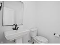 Modern bathroom featuring a sleek pedestal sink and minimalist design with white walls at 443 Flora Pl, Carmel, IN 46290