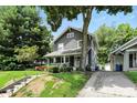 Traditional home featuring well-manicured landscaping, a quaint front porch, and mature trees at 5922 Broadway St, Indianapolis, IN 46220