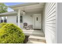 Inviting front porch featuring a cozy chair, side table, and hanging lantern next to the front door at 5986 Regency Dr, Columbus, IN 47203