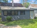 View of the house exterior with gray siding, visible back entrance and chimney at 711 W Centennial Ave, Muncie, IN 47303