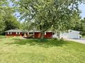 View of the exterior featuring brick siding, landscaping, and a large shade tree at 725 N State Road 75, Lebanon, IN 46052