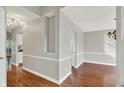 Spacious hallway with hardwood floors, neutral paint, and entryways to dining and kitchen areas at 9055 Glass Chimney Ln, Fishers, IN 46037